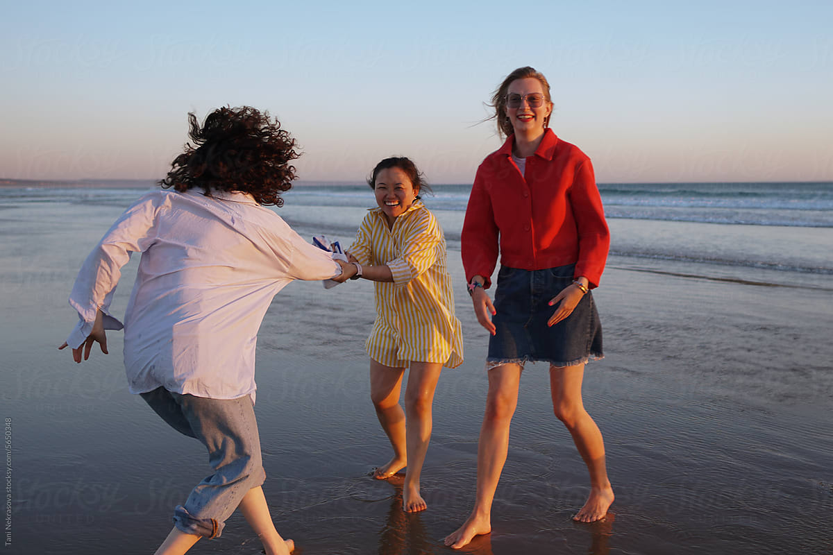 Three young female friends having fun by the ocean. Friendship