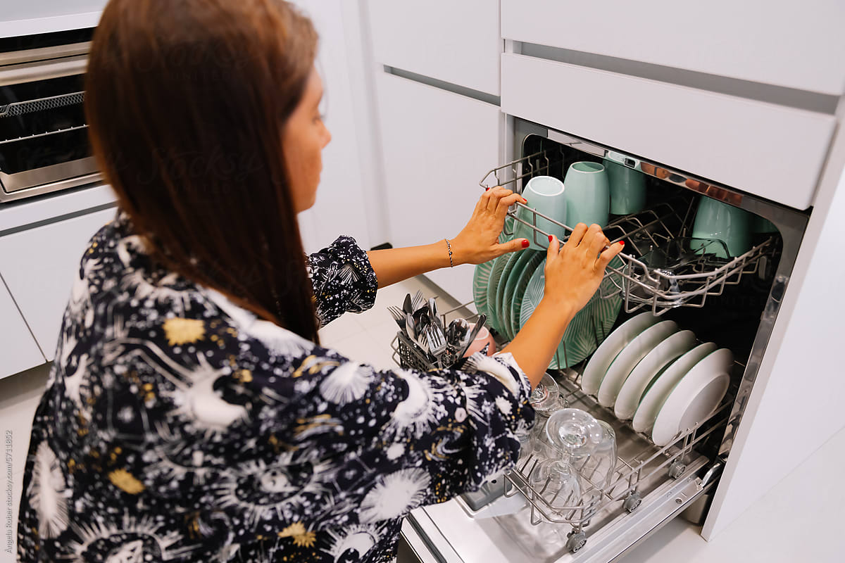 Young woman organizing the dishwasher