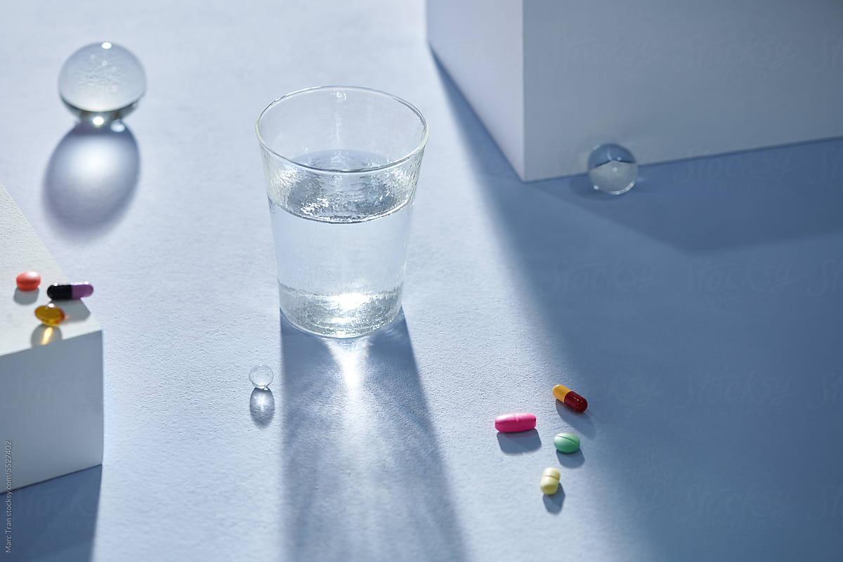 Water in a clear glass Cup and colorful pill tablets