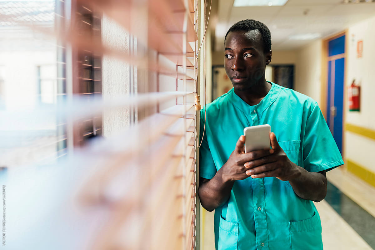 Black young nurse man using mobile