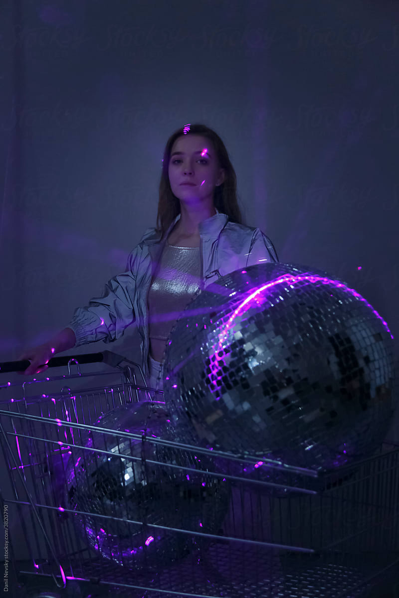 Woman with shopping cart and disco balls in ultraviolet lights