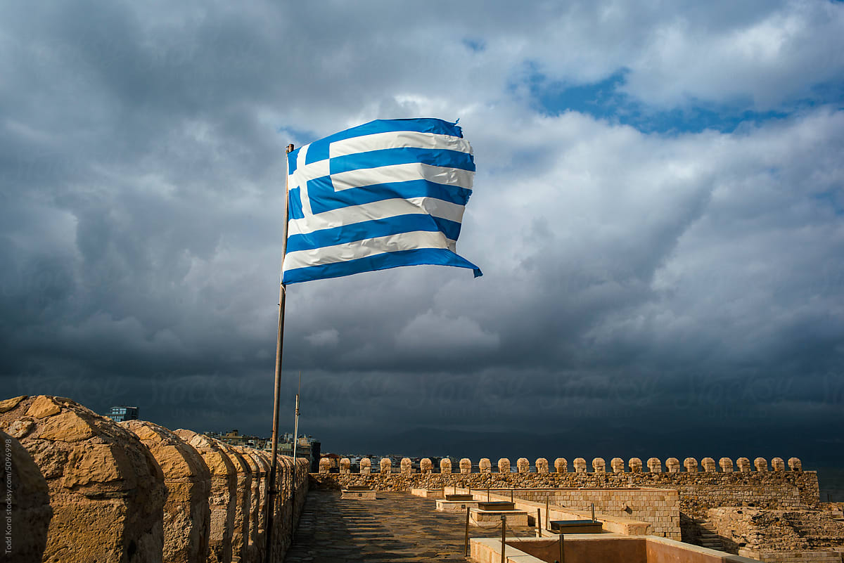 A Greek flag flies over a castle.