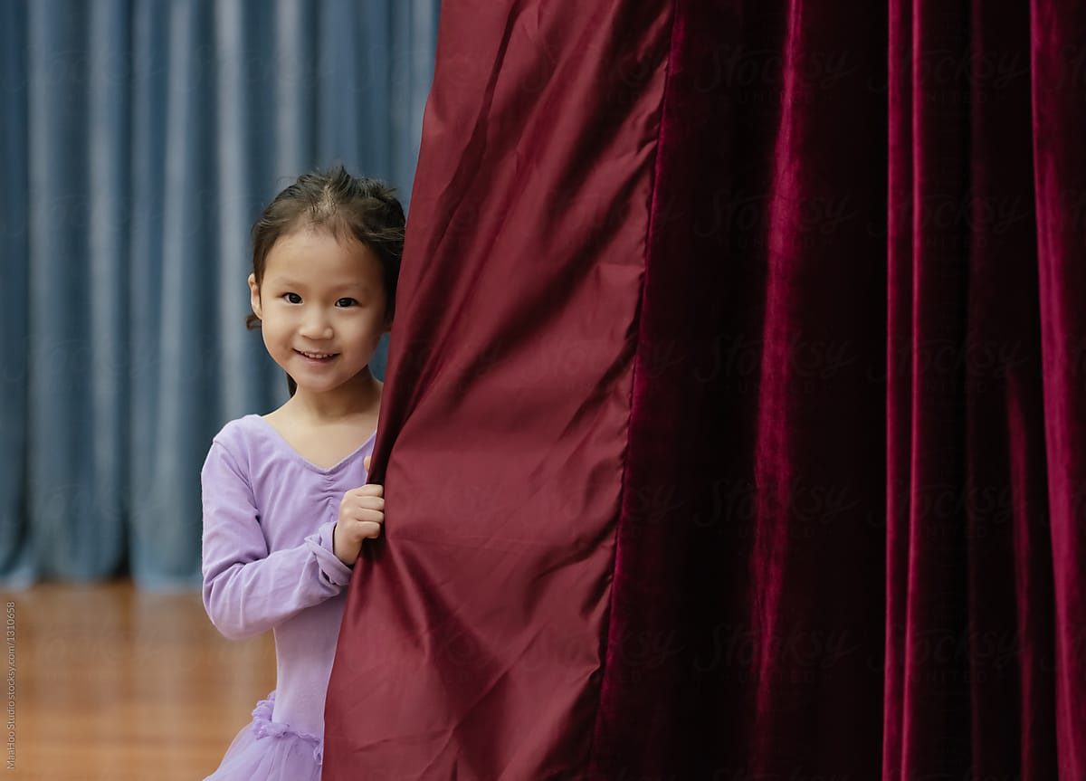 Little girl peeking out from the curtain