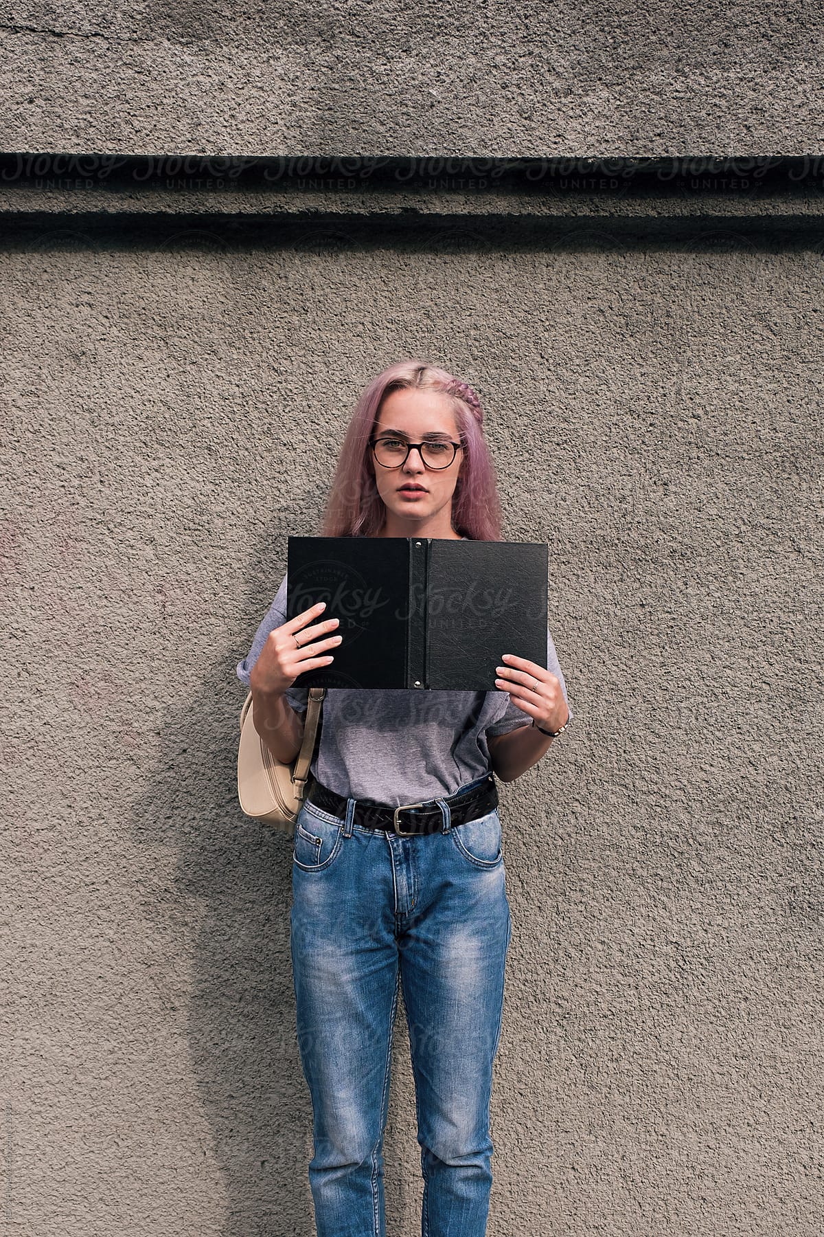 Young woman with pink hair holding open notebook with black cover