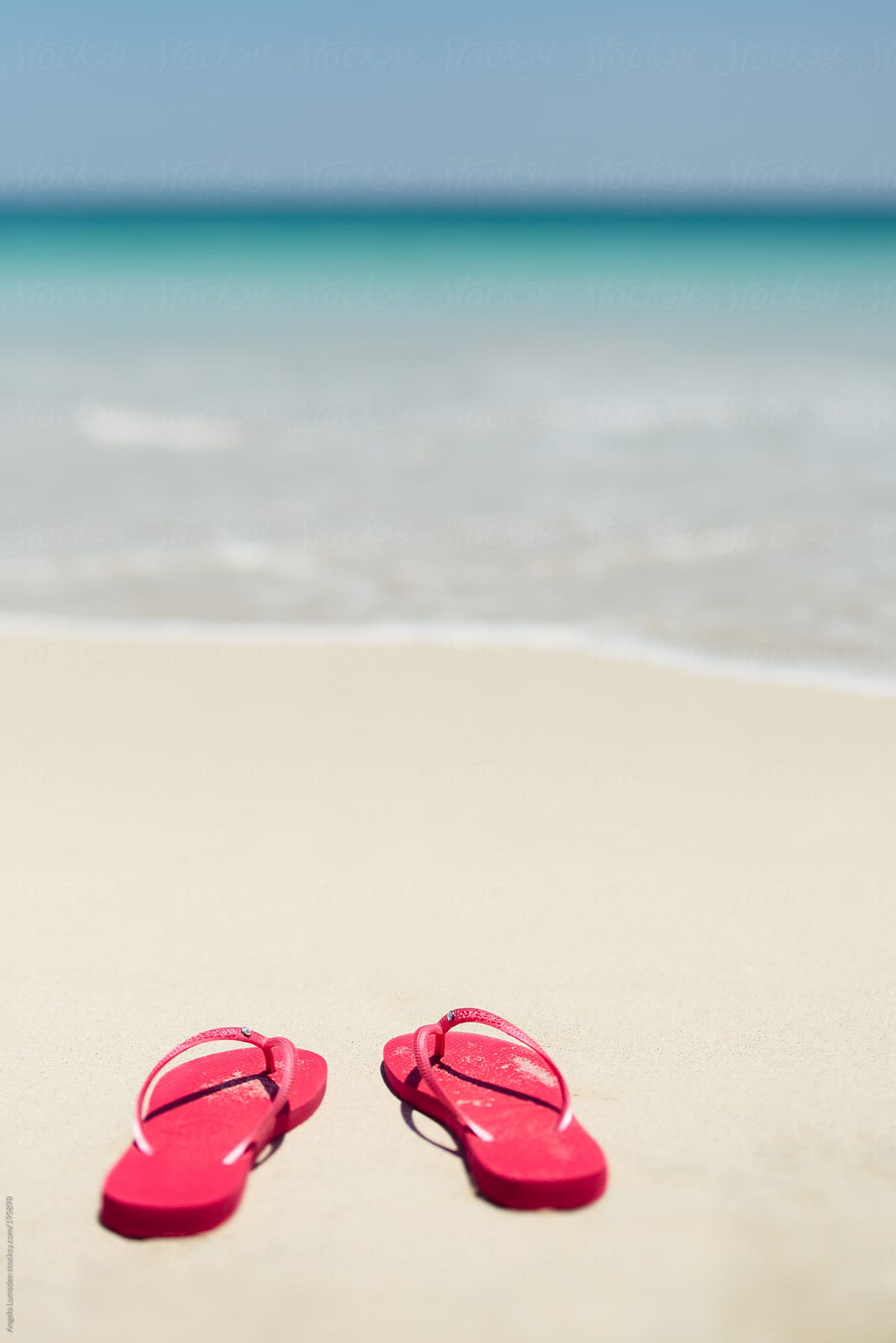 Red flip flops in the sand beside the 