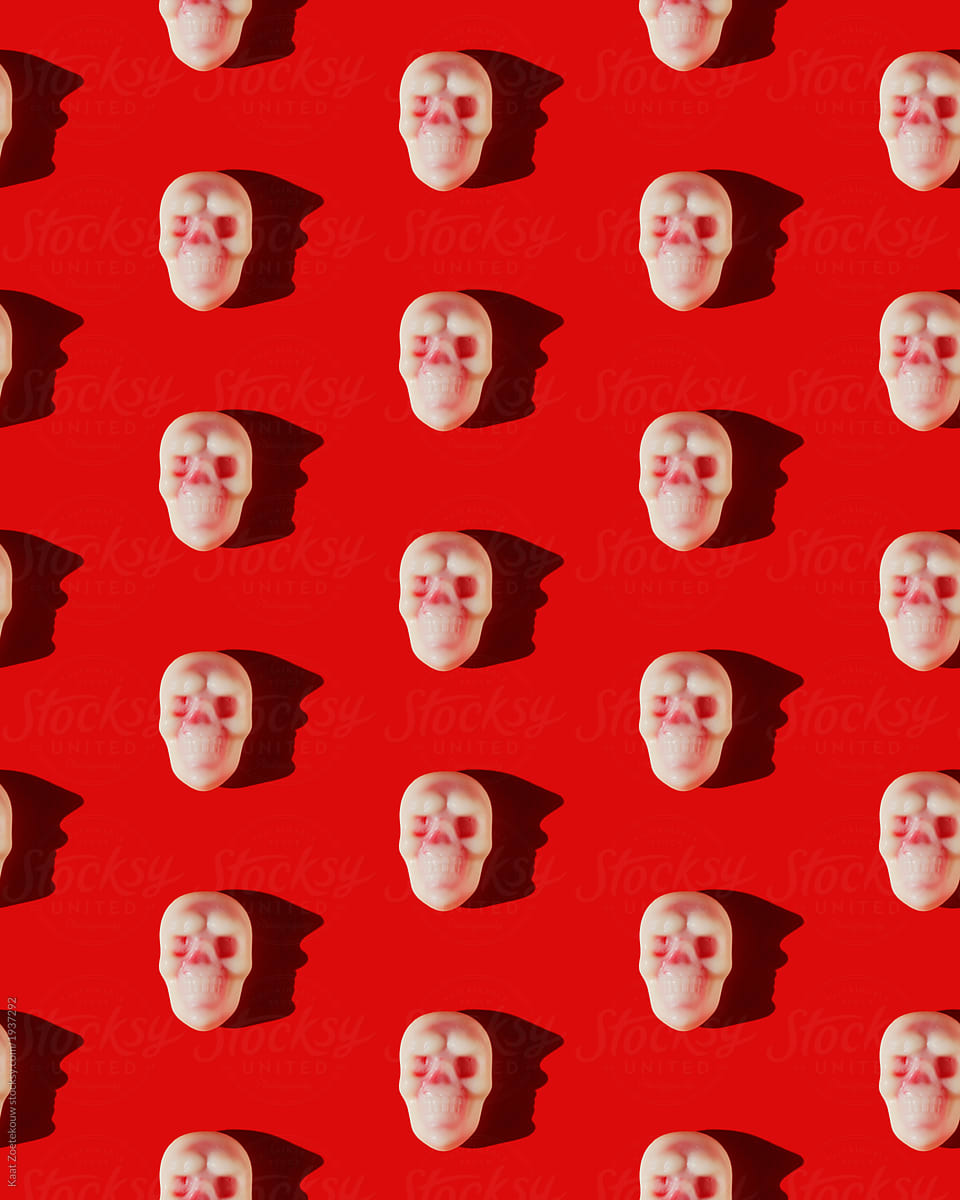 Pattern of white and red Halloween-themed skull candies on a red background