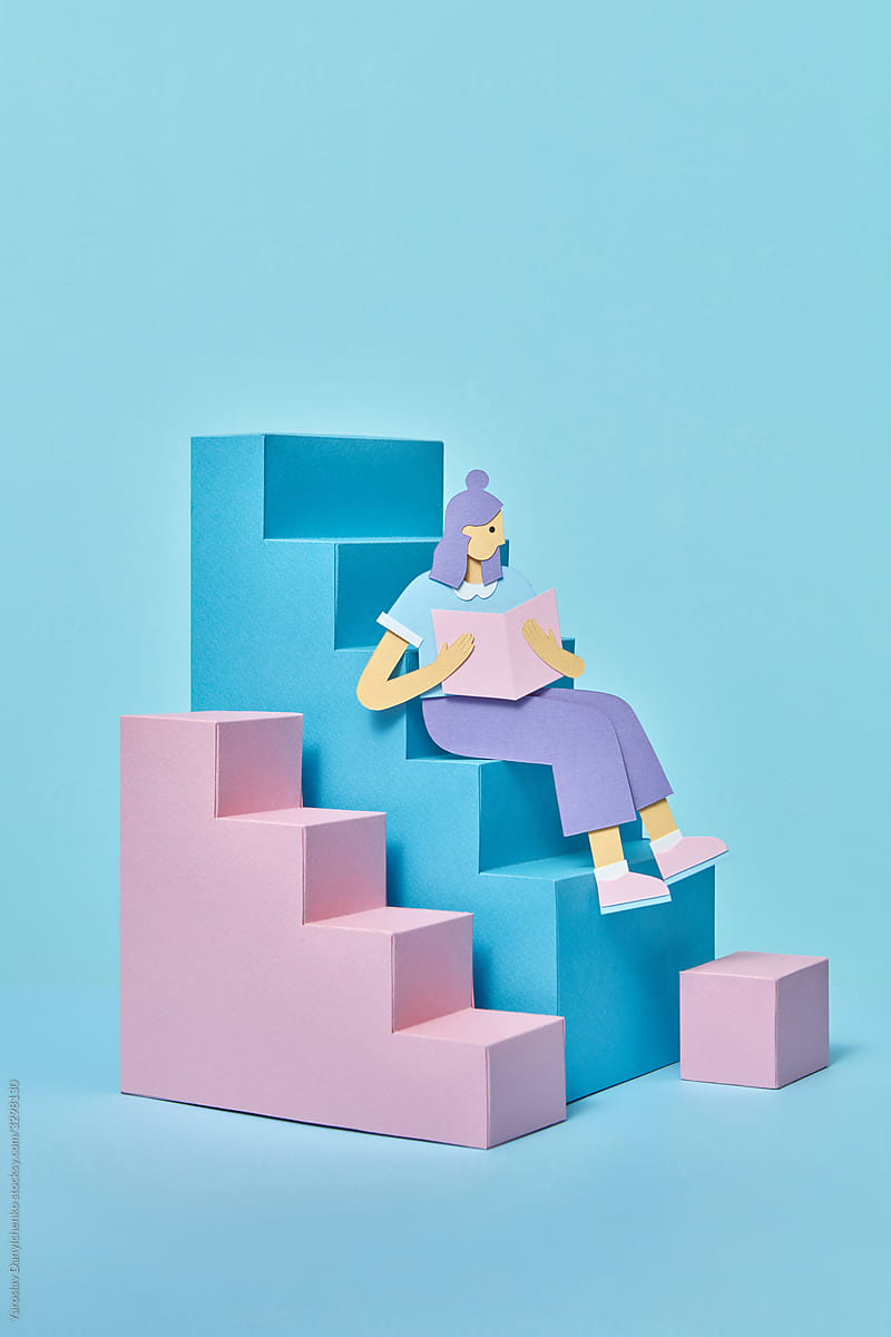 Papercraft girl is reading book on the staircase.