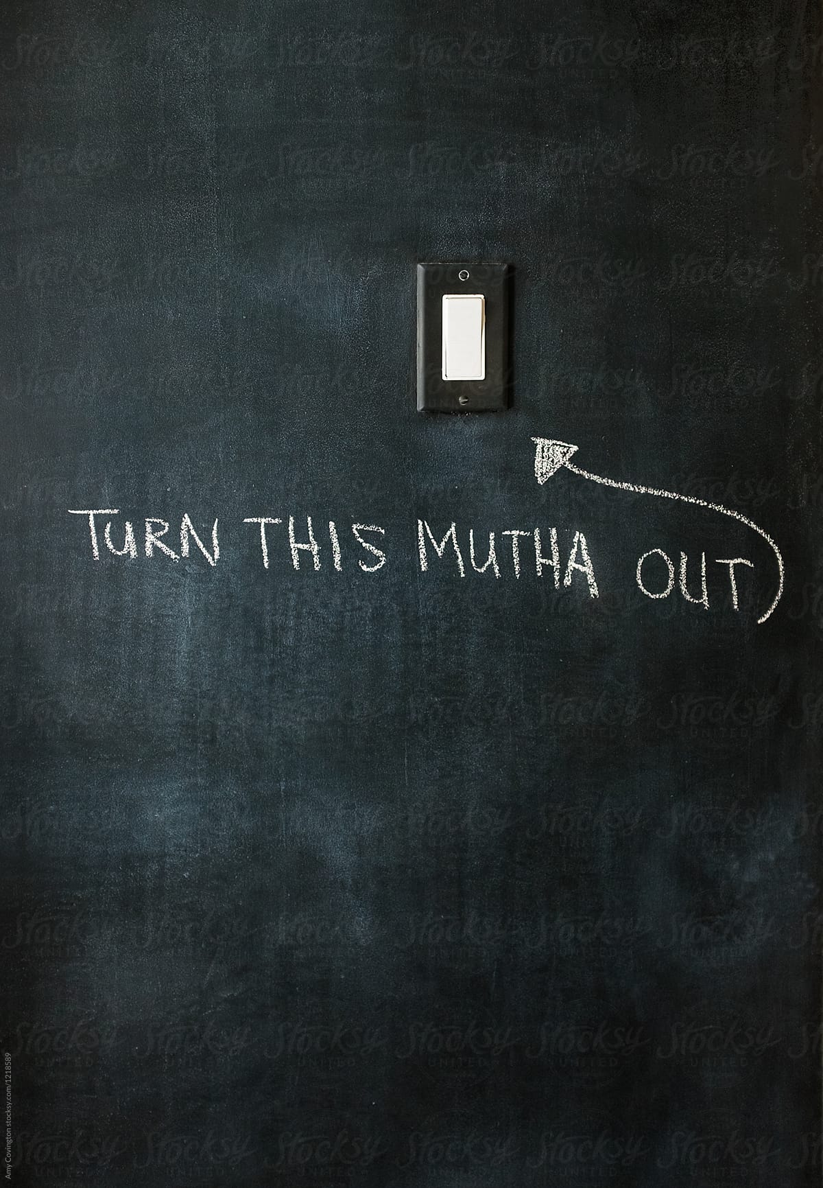 Black wall with a message written below a light switch