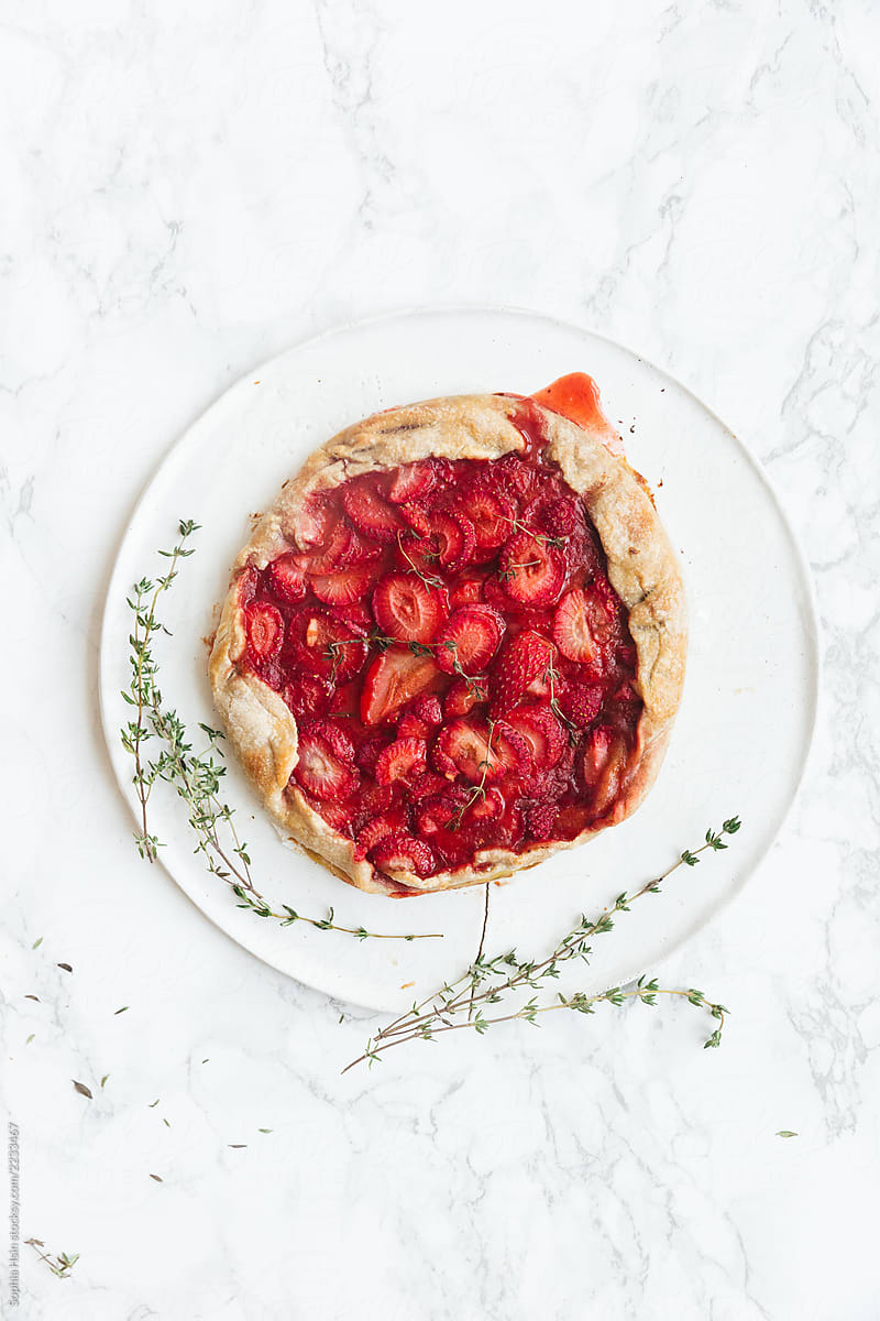 Delicious fresh baked vegan strawberry galette with thyme on white ceramic plate