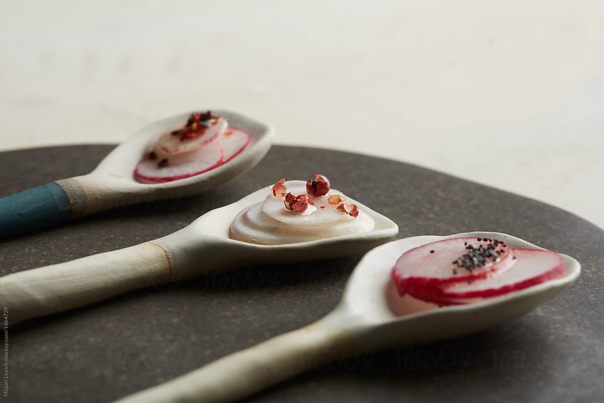 Trio of ceramic spoons with sliced raw vegetables