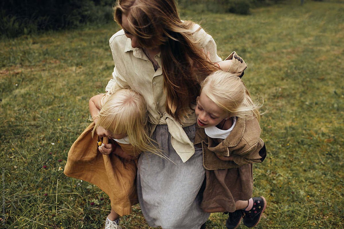 Mom picked up her two little daughters under the arms while walking.