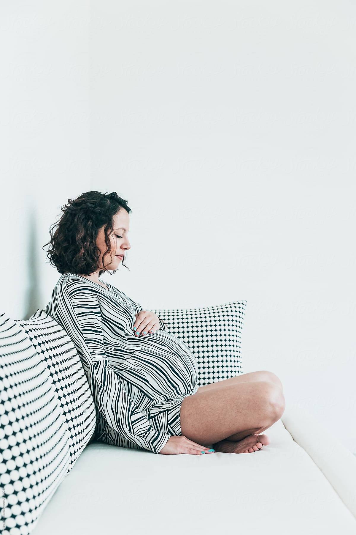 Pregnant woman sitting on a white sofa