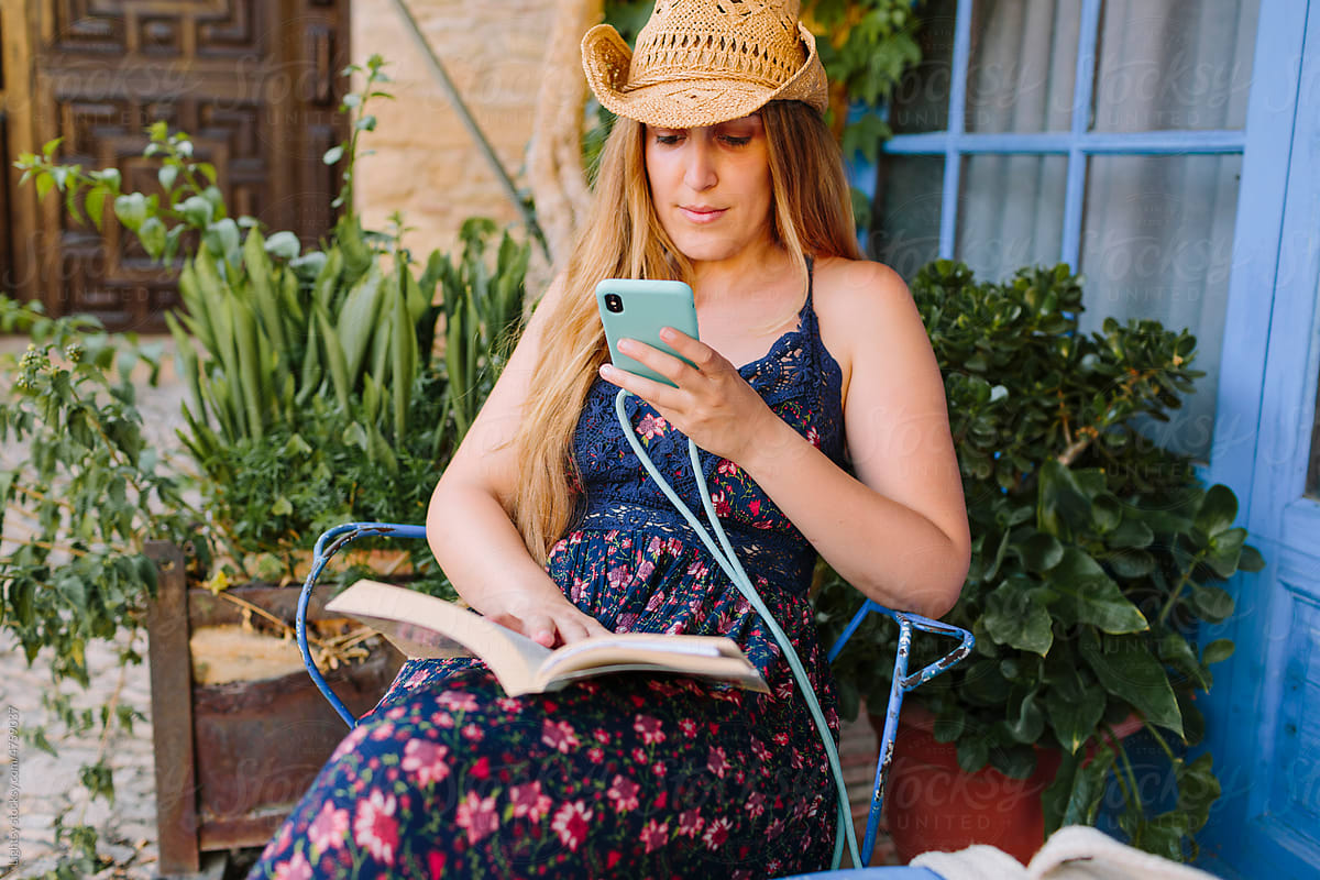 Woman reading a book and looking at her smartphone