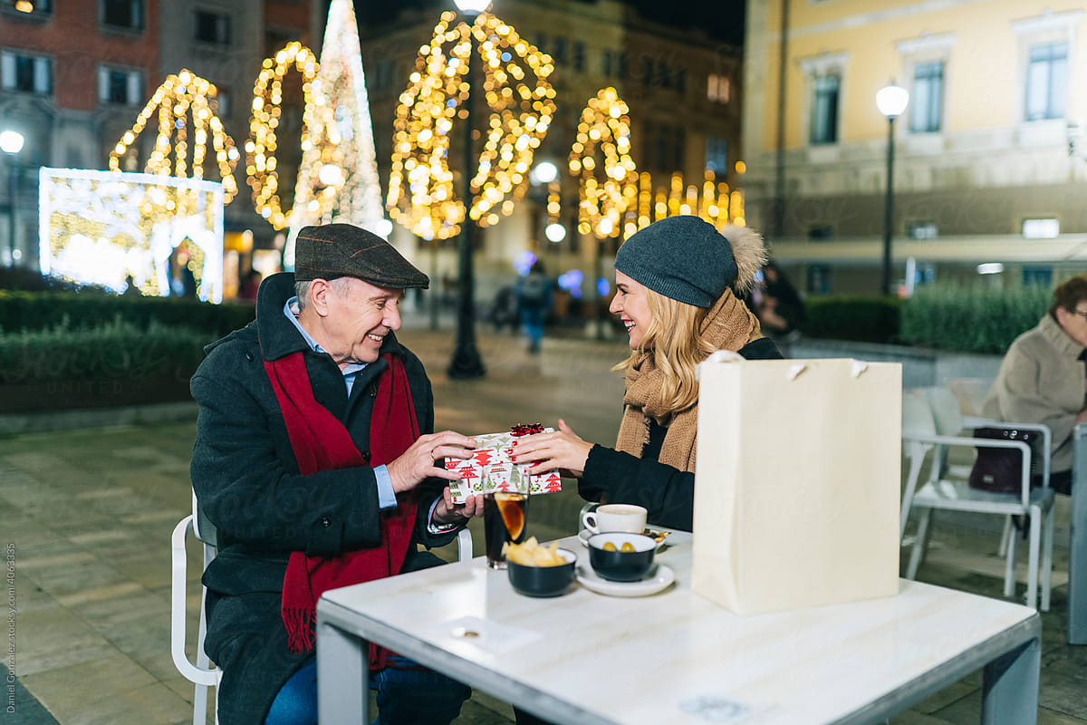 Man and woman with Xmas gift in street cafe
