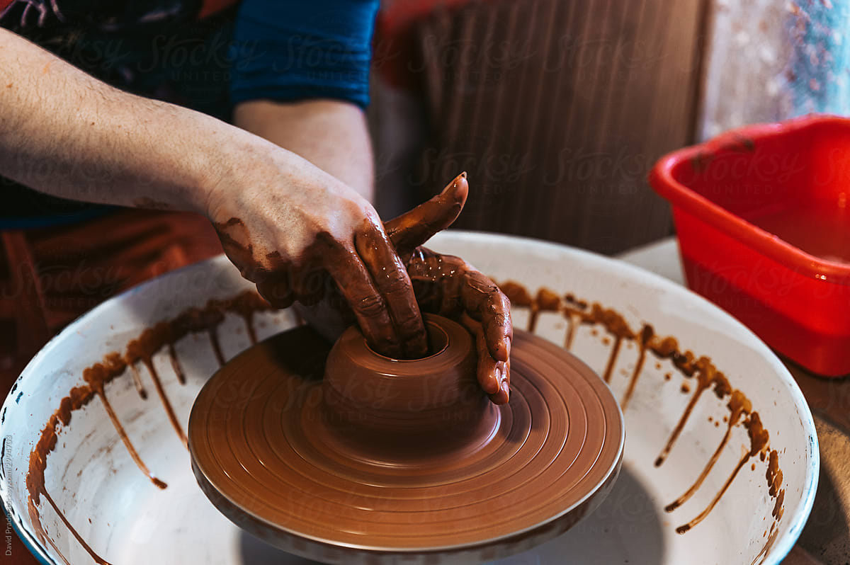 Anonymous young woman ceramist working with pottery wheel in workshop