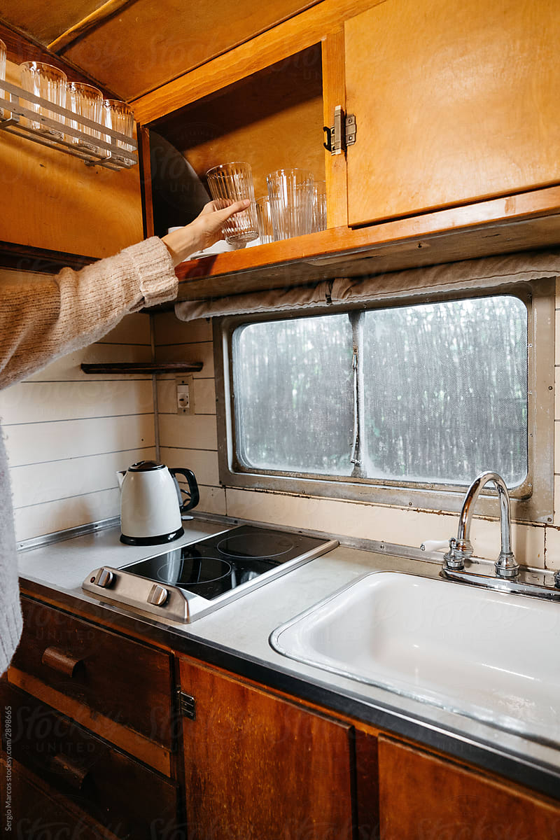 Anonymous woman taking a glass from kitchen cabinet