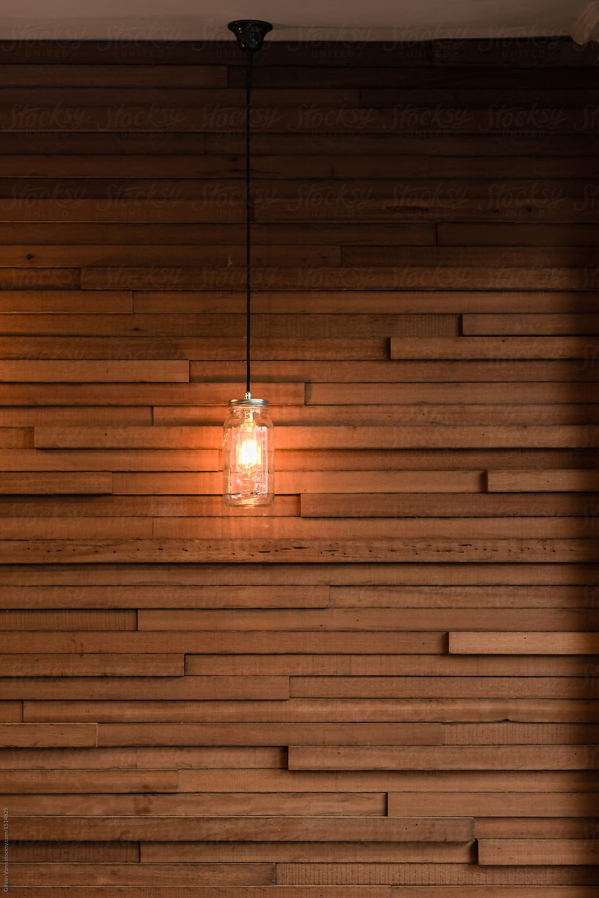 hanging light in mason jar, against a timber slat wall