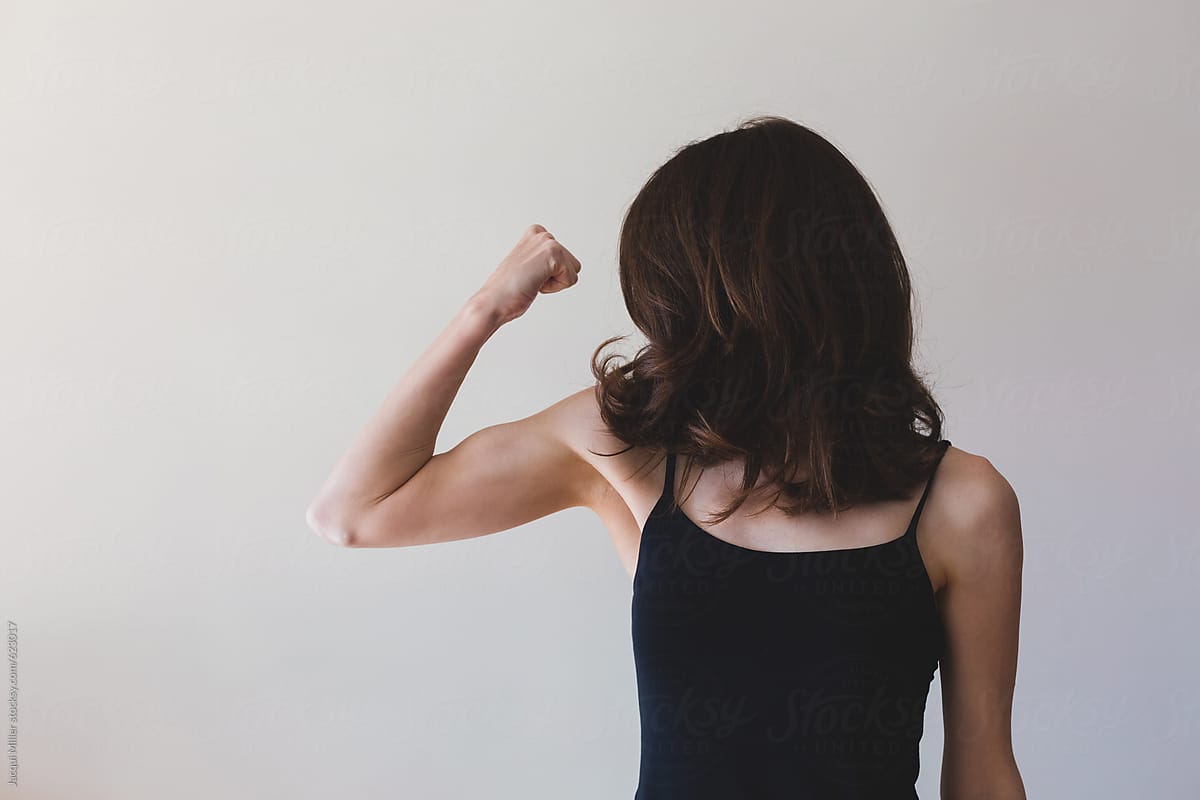 Thin Woman Flexing Her Arm Muscle - Horizontal by Stocksy