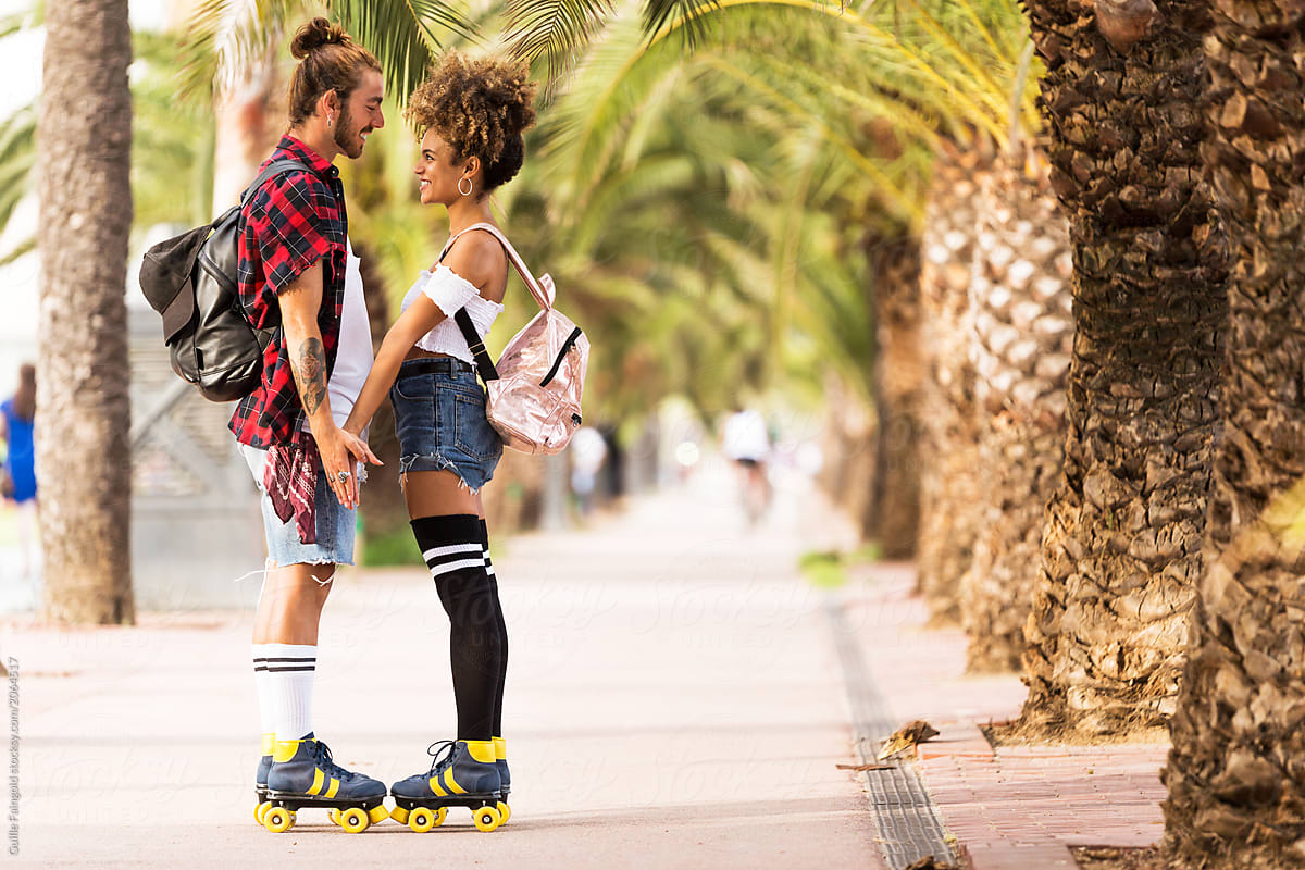 Happy couple in rollerblades surrounded by palm trees.