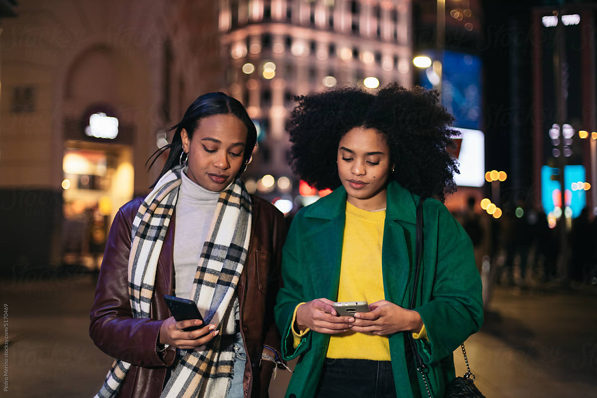 Young women using smartphone in the city at night