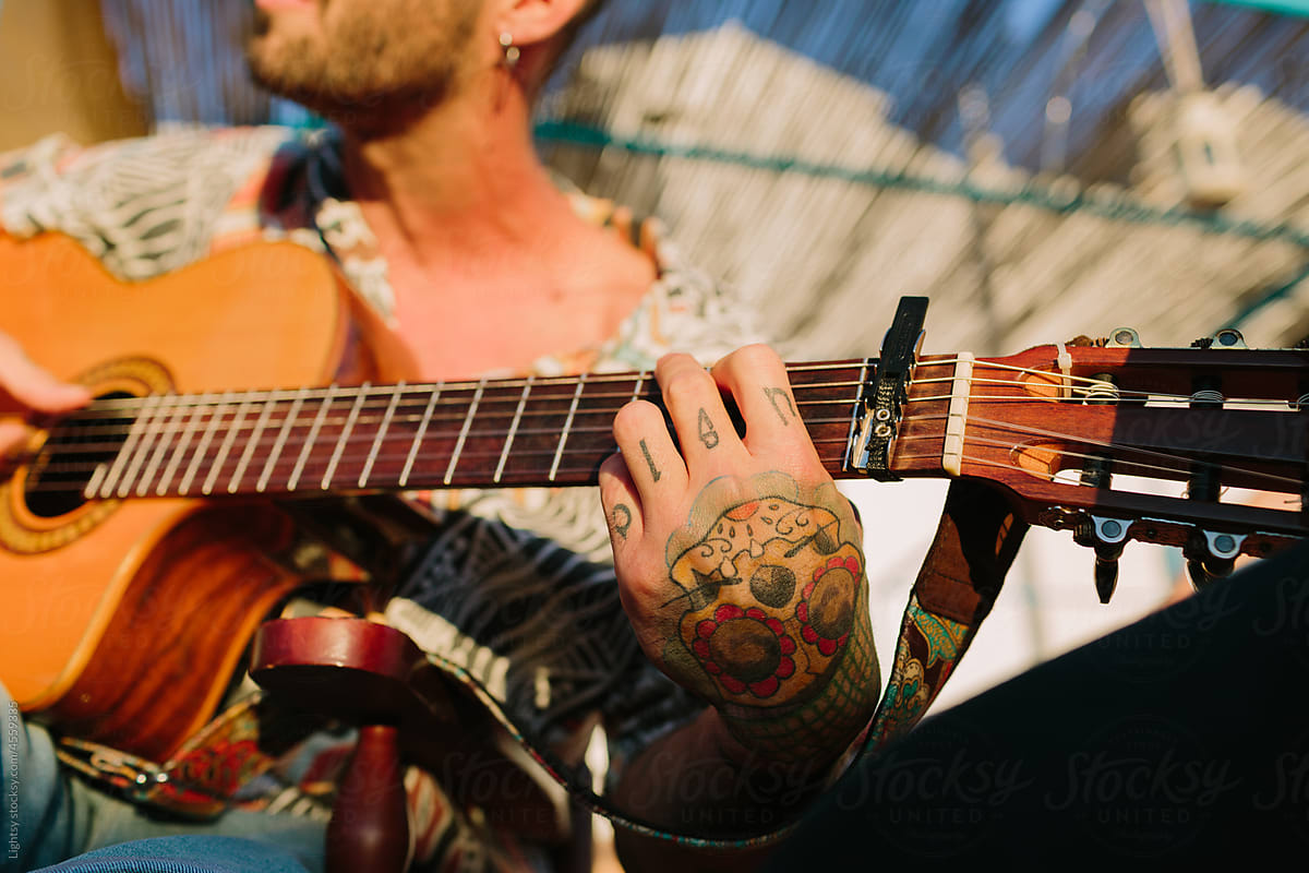 Hands with tattoos playing a spanish guitar