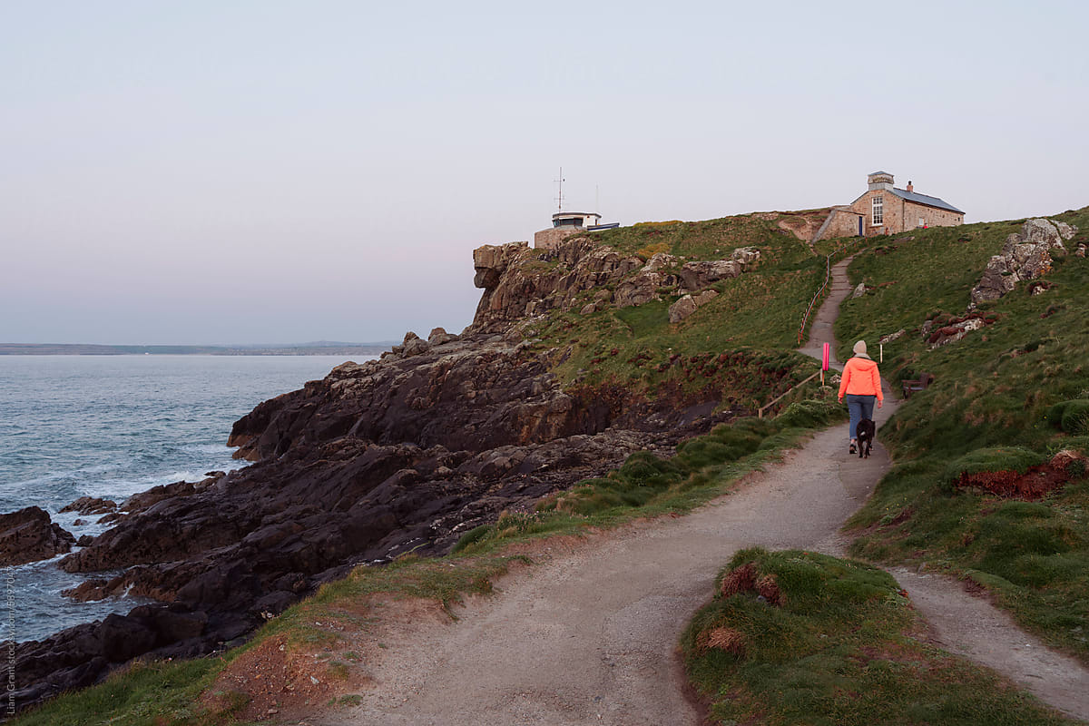 Female walking the island in St Ives with her dog at sunset