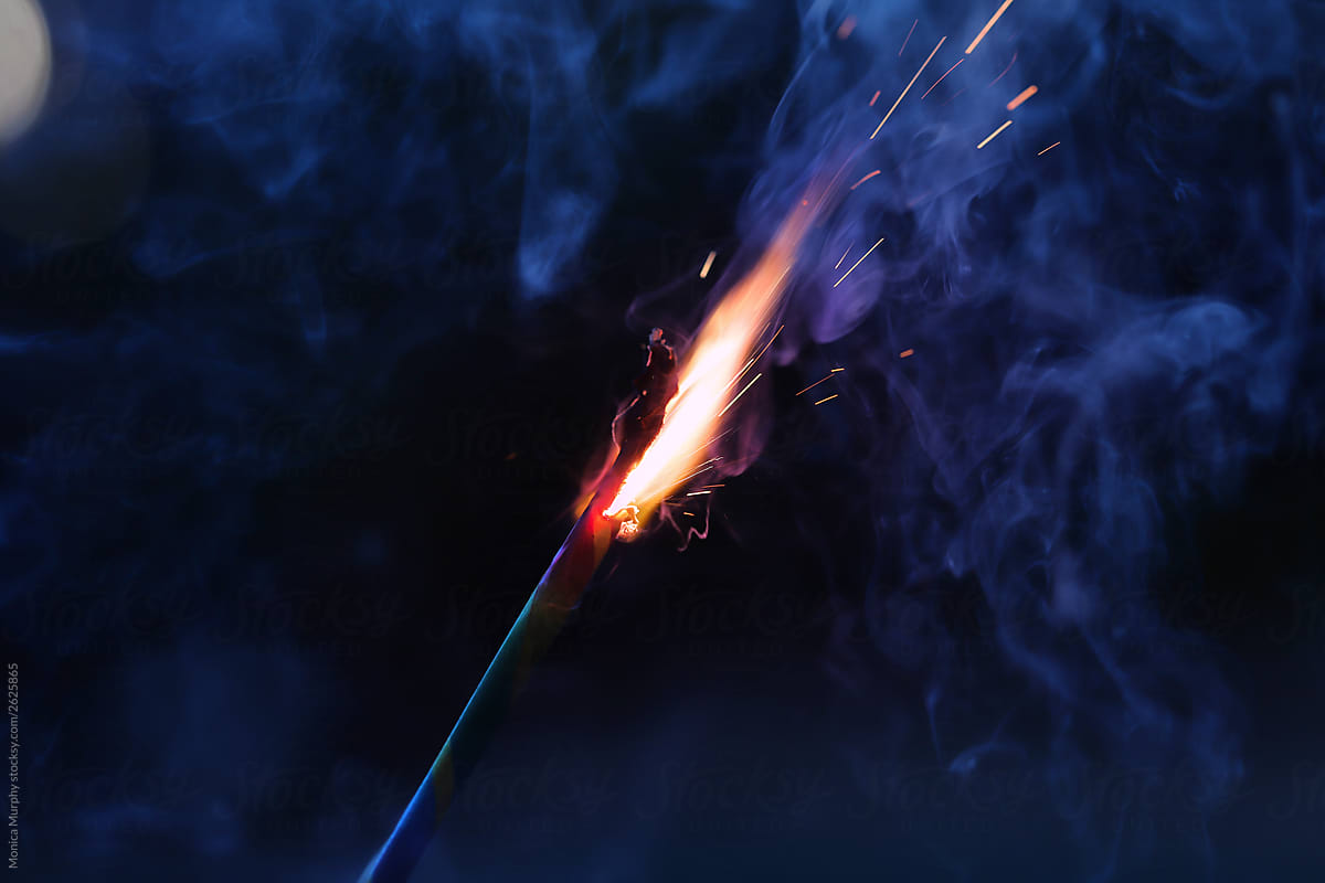 Close up of firework sparkler on blue smokey background