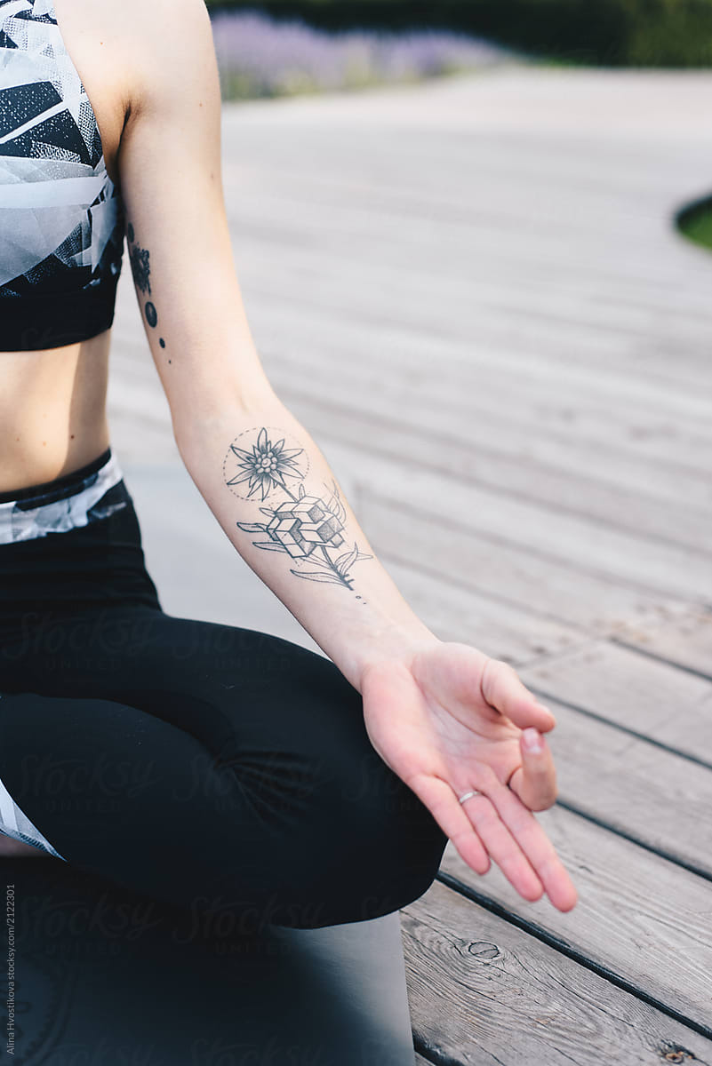 Crop tattooed woman in asana meditating