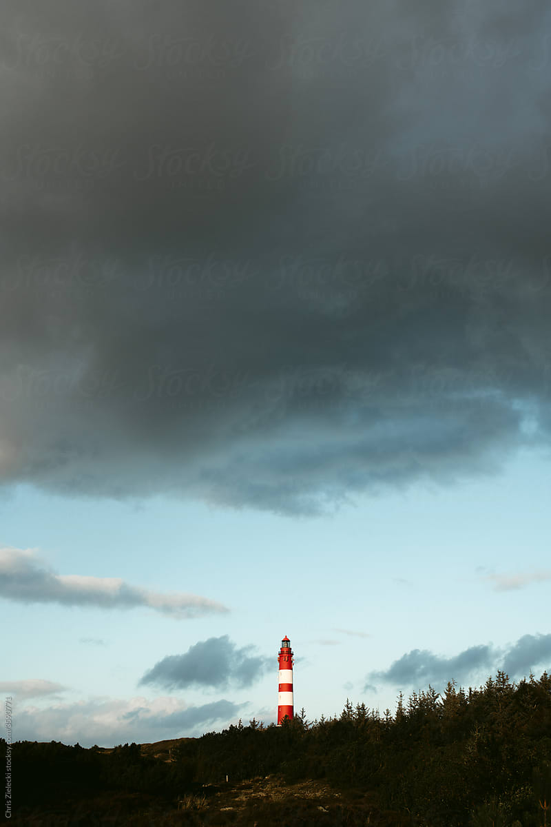 Lighthouse near forest on cloudy day