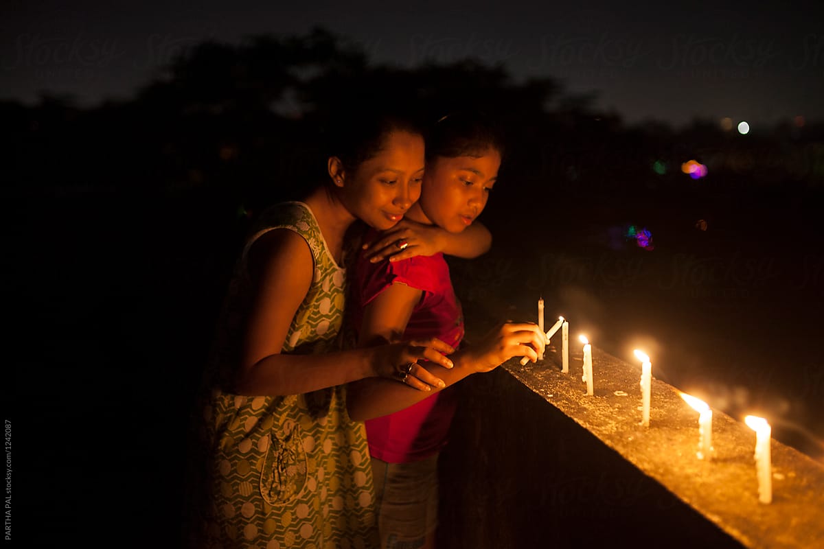 Teenage girl and young woman lighting candle at night  in outdoor