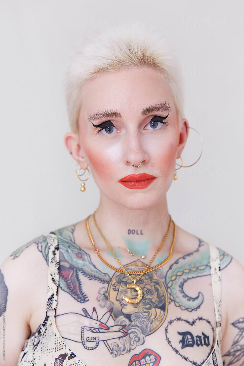 A strong portrait of a beautiful and eccentric woman with body tattoos and gold jewelries.