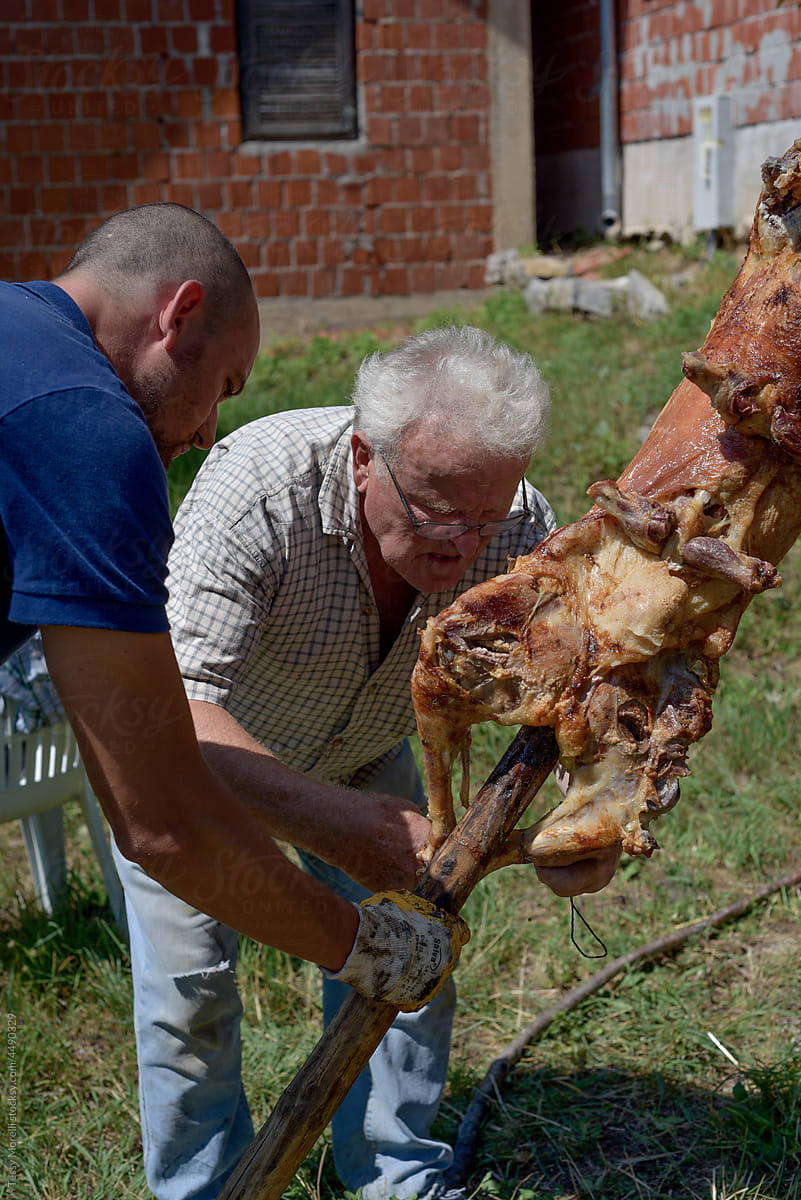 Father and son dealing with the roasted lamb after bbq