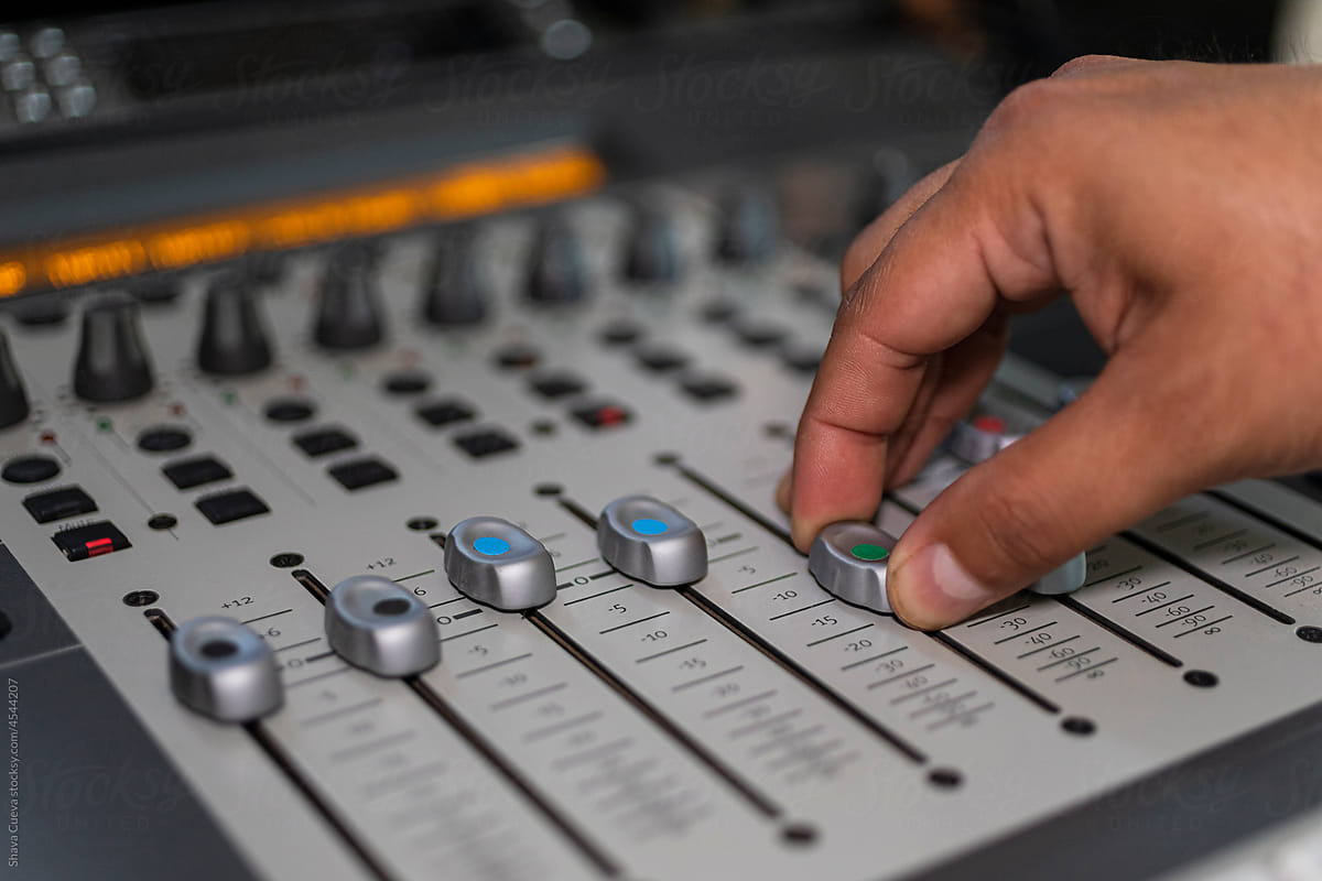 closeup of male right hand moving red buttons from an audio console