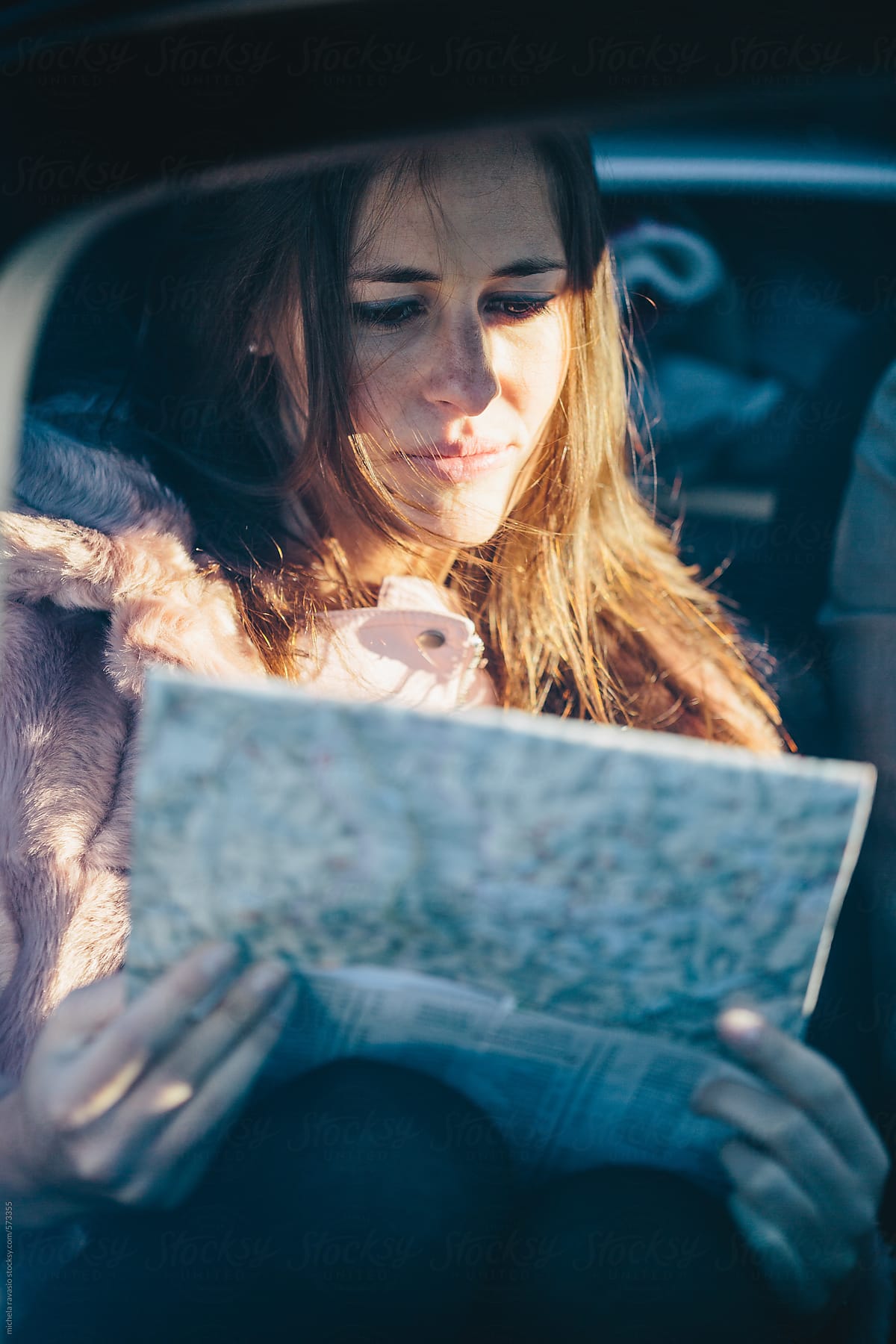 Woman sitting in car checks the road map