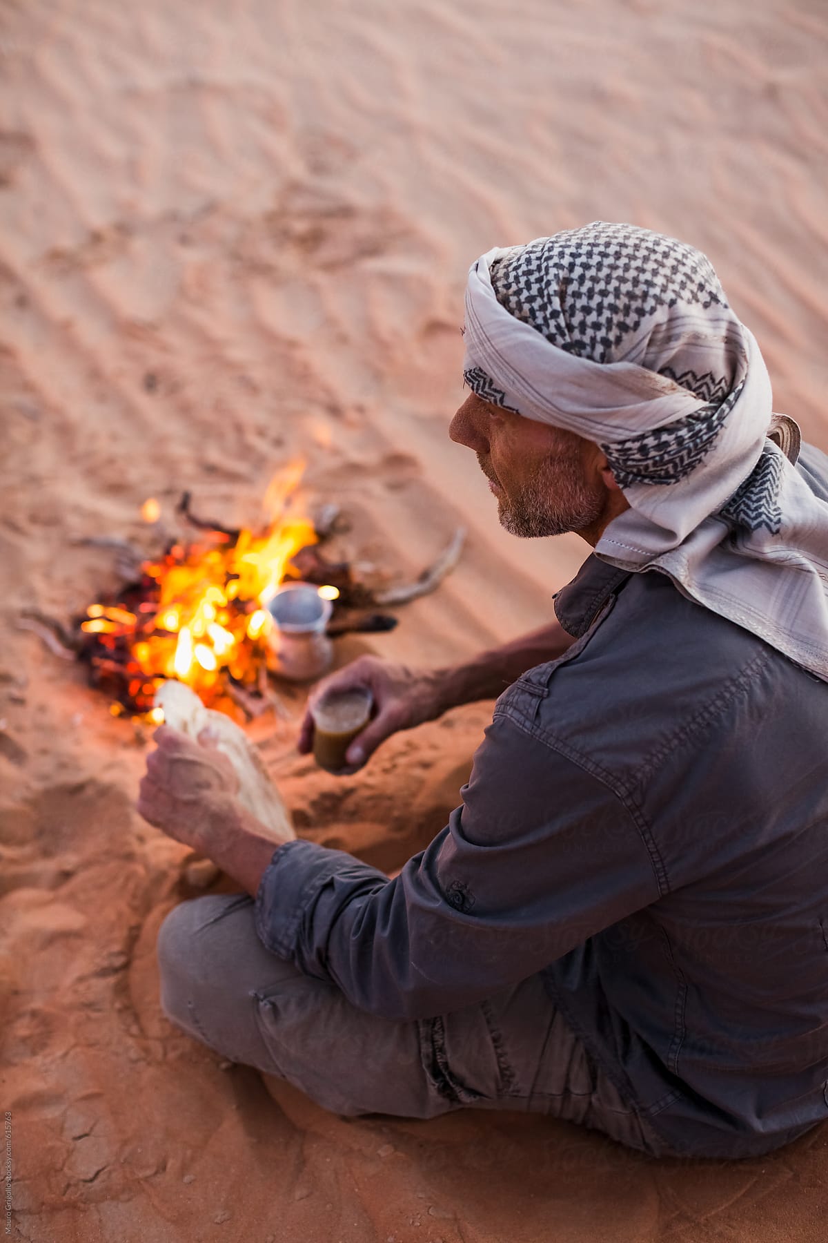 Man sitting in front of a campfire to eat
