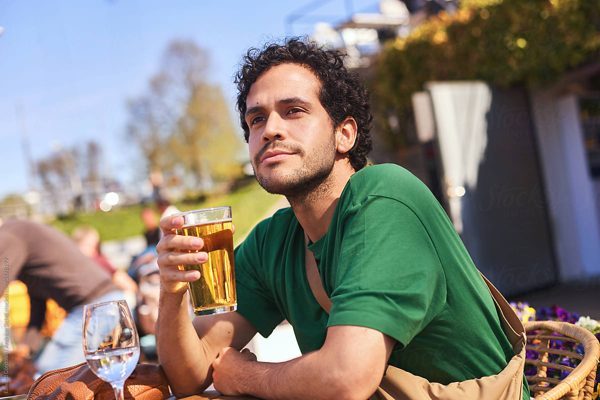 A young, happy tourist enjoying a beer at a terrace.