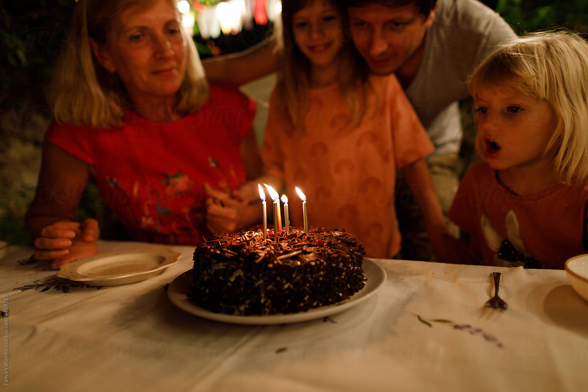 A little girl is blowing candles on the cake