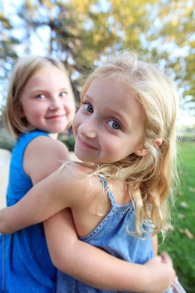 Sisters Hugging Wearing Blue One Looking Over Shoulder By Stocksy Contributor Dina Marie