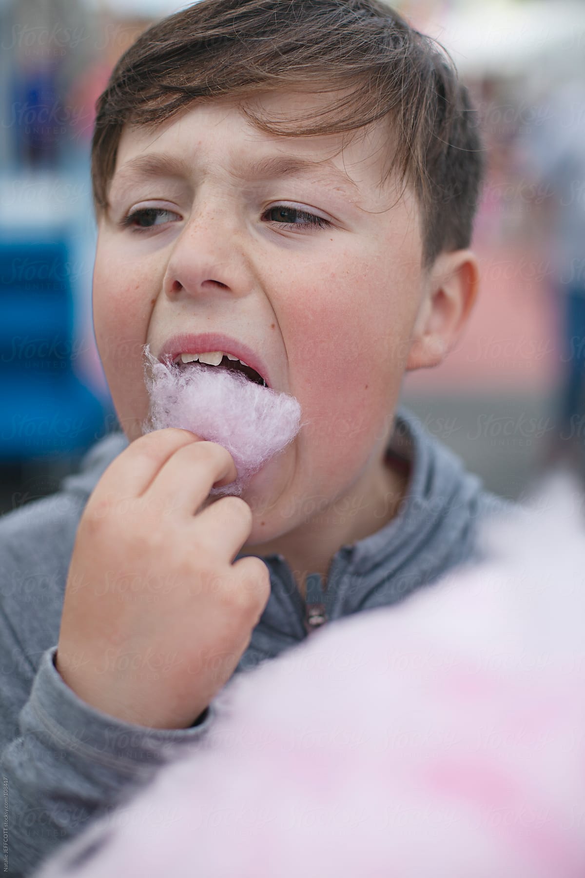 young boy eating candy floss at a fair