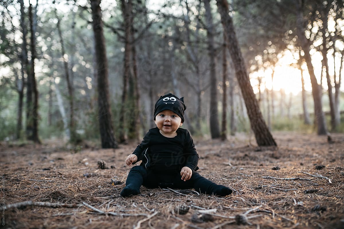 Lovely baby in bat costume in forest.