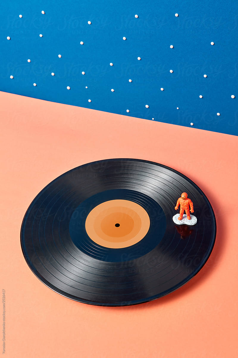 Plastic toy of astronaut on a vinyl record on a duotone stars background.