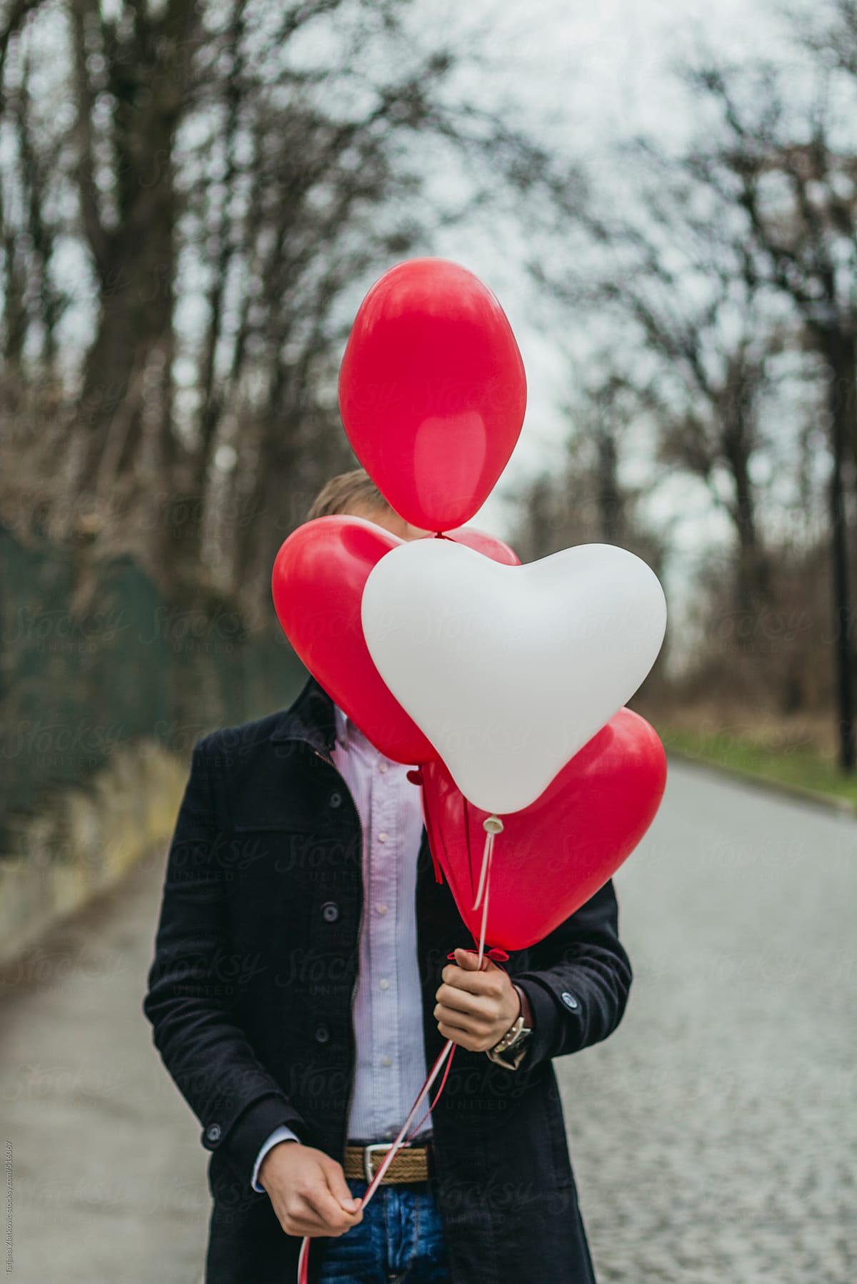 A young man holding heart shaped balloons