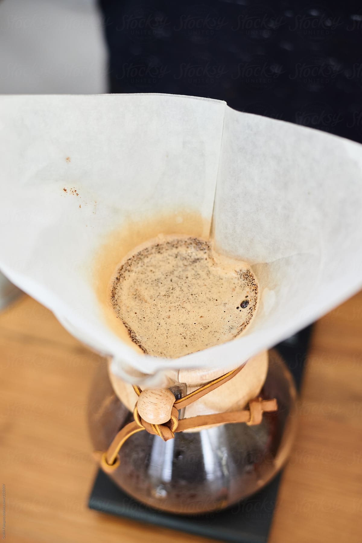 Close-up of chemex with paper filter producing coffee.