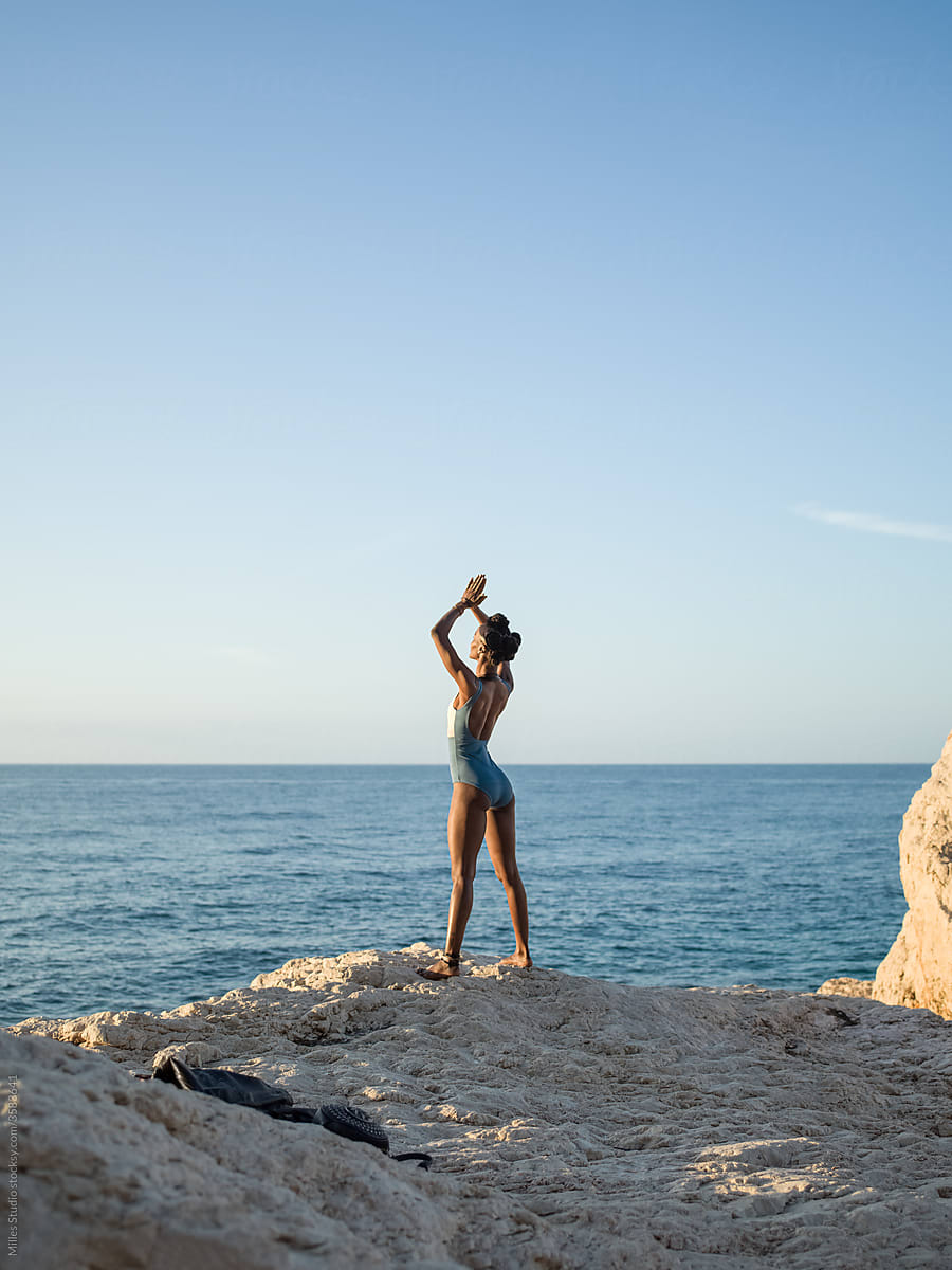 Black woman meditating on seashore in morning