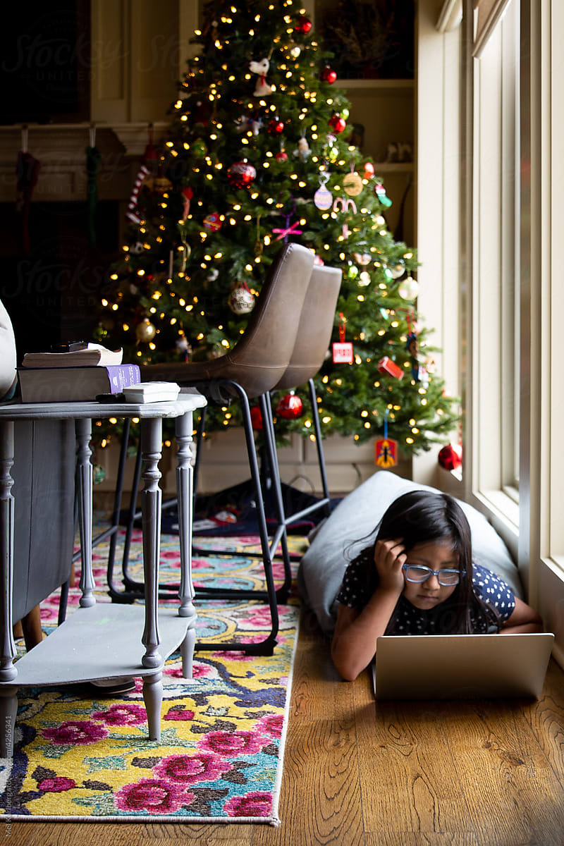 Young girl on computer in front of Christmas tree