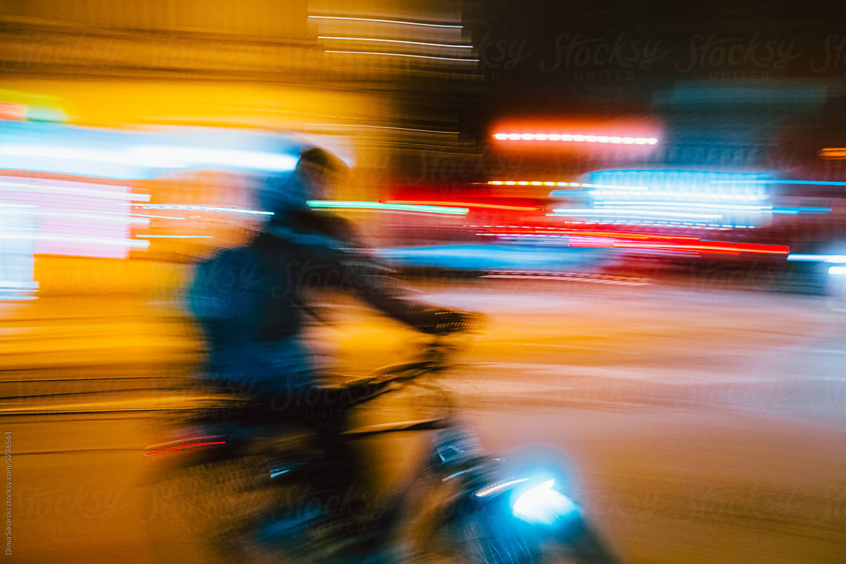 Conceptual photo of a delivery man on a bike in a night city at speed
