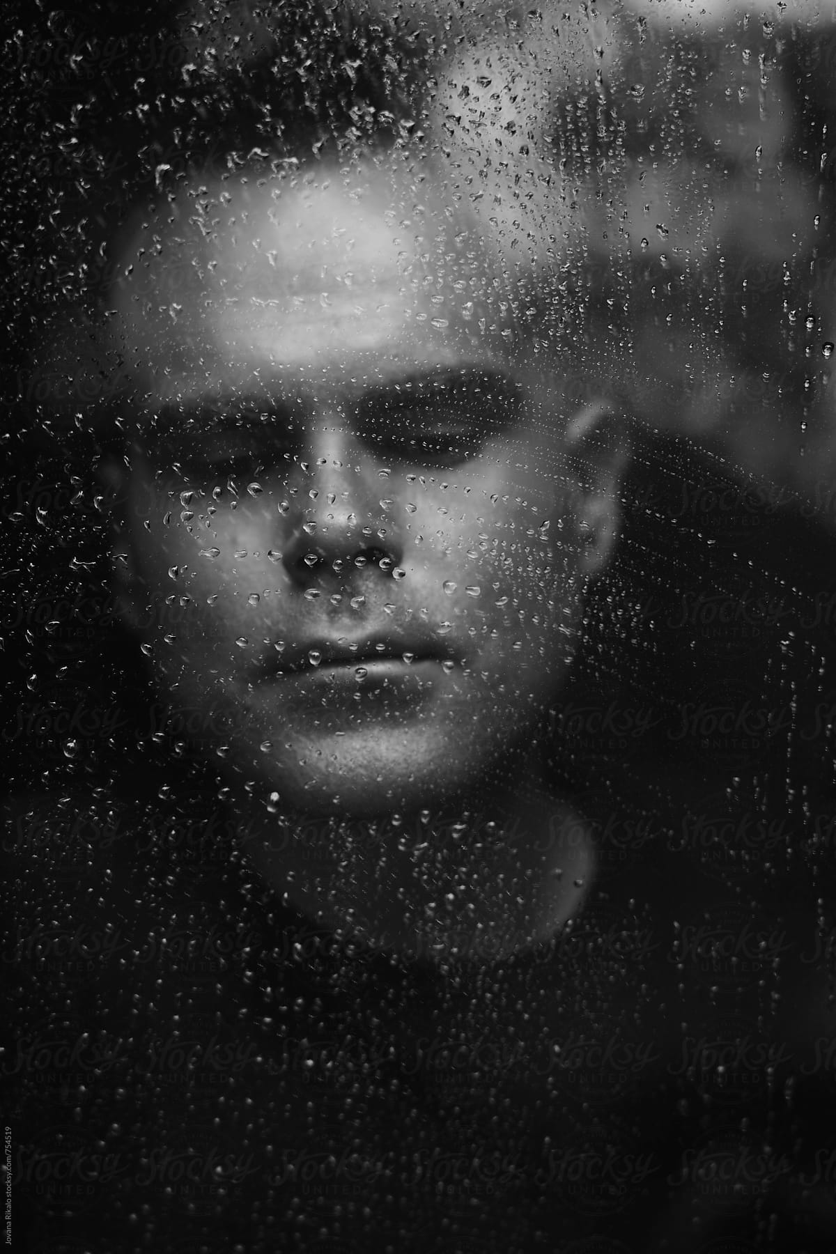 Portrait of a man watching rain through window