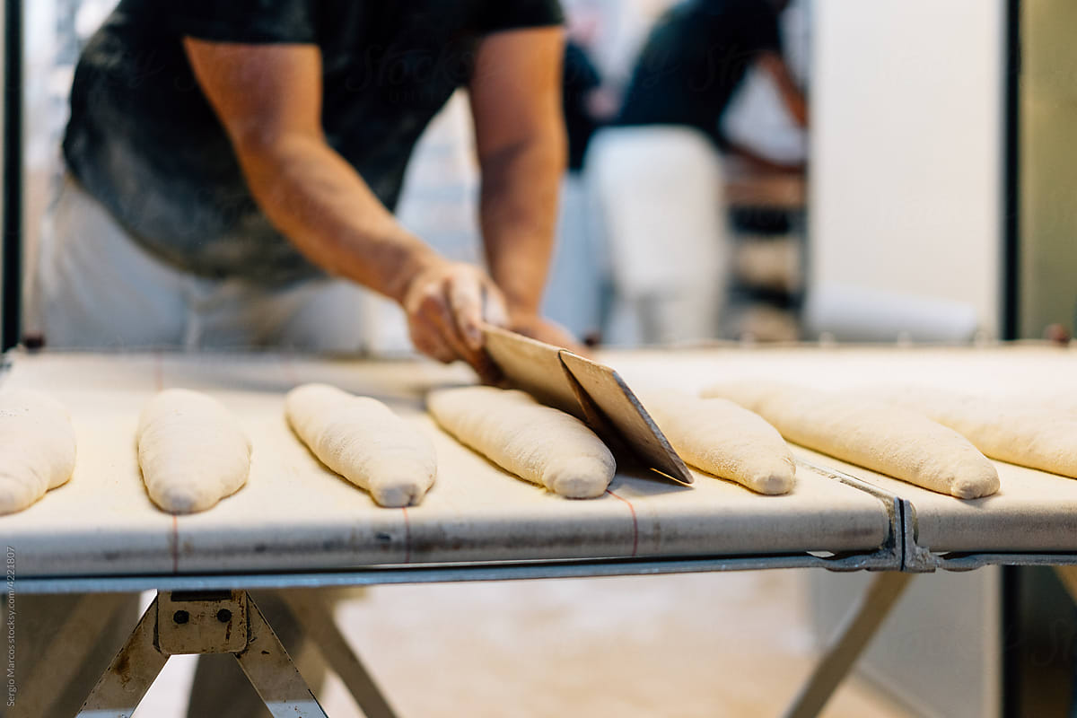 Baker arranging bread on conveyor