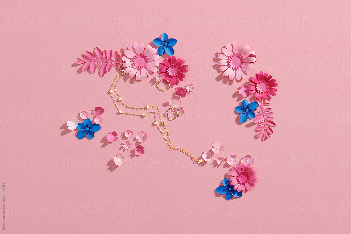 Paper tropical leaves and flowers over pink pastel background.