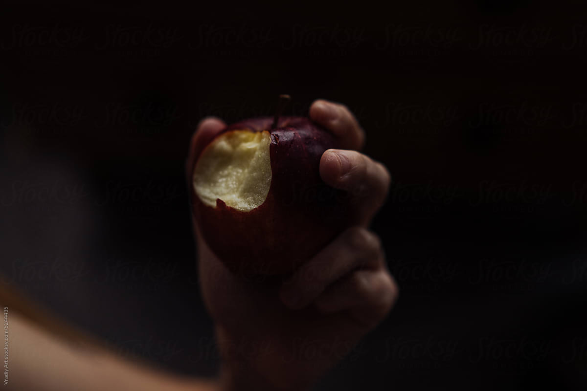 An apple in the hands in the dark